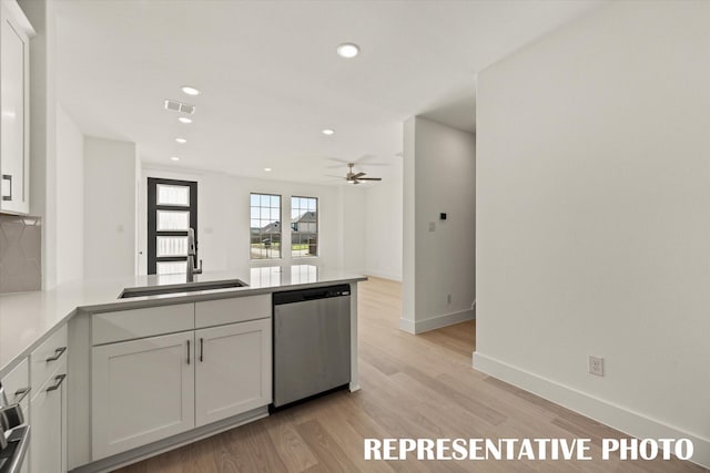 kitchen featuring sink, light hardwood / wood-style floors, white cabinets, stainless steel dishwasher, and kitchen peninsula