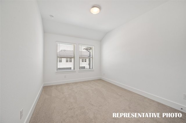 carpeted empty room with vaulted ceiling