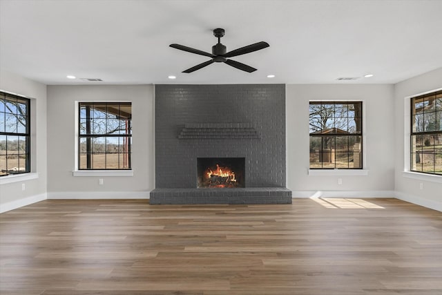 unfurnished living room featuring plenty of natural light, hardwood / wood-style floors, and a brick fireplace