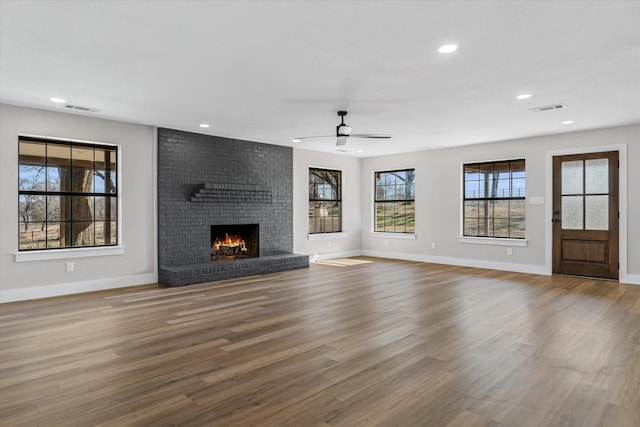 unfurnished living room with a brick fireplace, hardwood / wood-style flooring, and ceiling fan