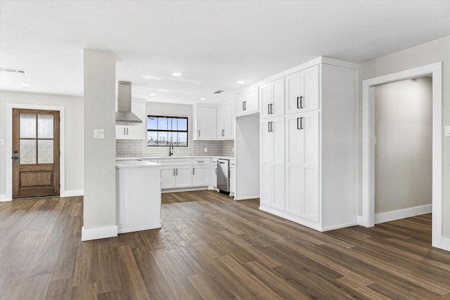 kitchen with dark hardwood / wood-style floors, tasteful backsplash, dishwasher, white cabinets, and wall chimney range hood