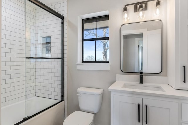 full bathroom featuring vanity, shower / bath combination with glass door, and toilet