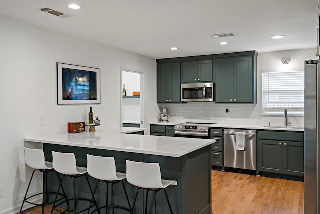 kitchen featuring stainless steel appliances, sink, a breakfast bar area, and kitchen peninsula