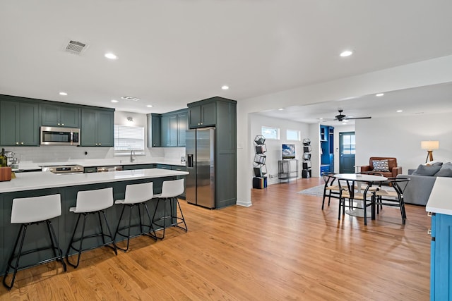 kitchen with stainless steel appliances, plenty of natural light, a breakfast bar, and light wood-type flooring