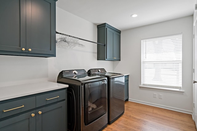 washroom featuring cabinets, a wealth of natural light, washer and clothes dryer, and light hardwood / wood-style floors