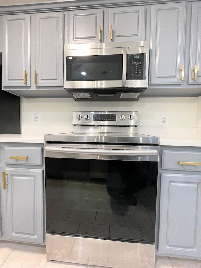 kitchen featuring gray cabinetry, stainless steel appliances, and light tile patterned flooring