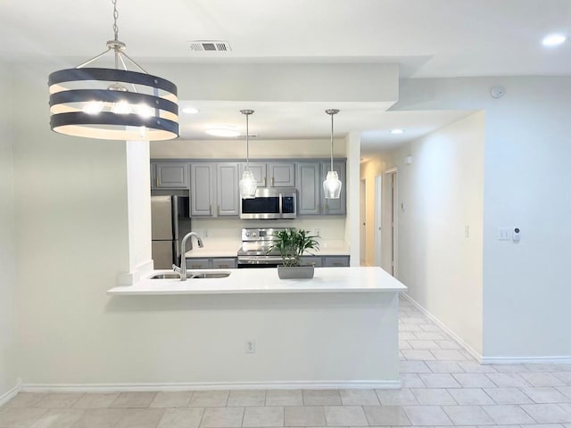 kitchen with gray cabinets, pendant lighting, sink, light tile patterned floors, and stainless steel appliances