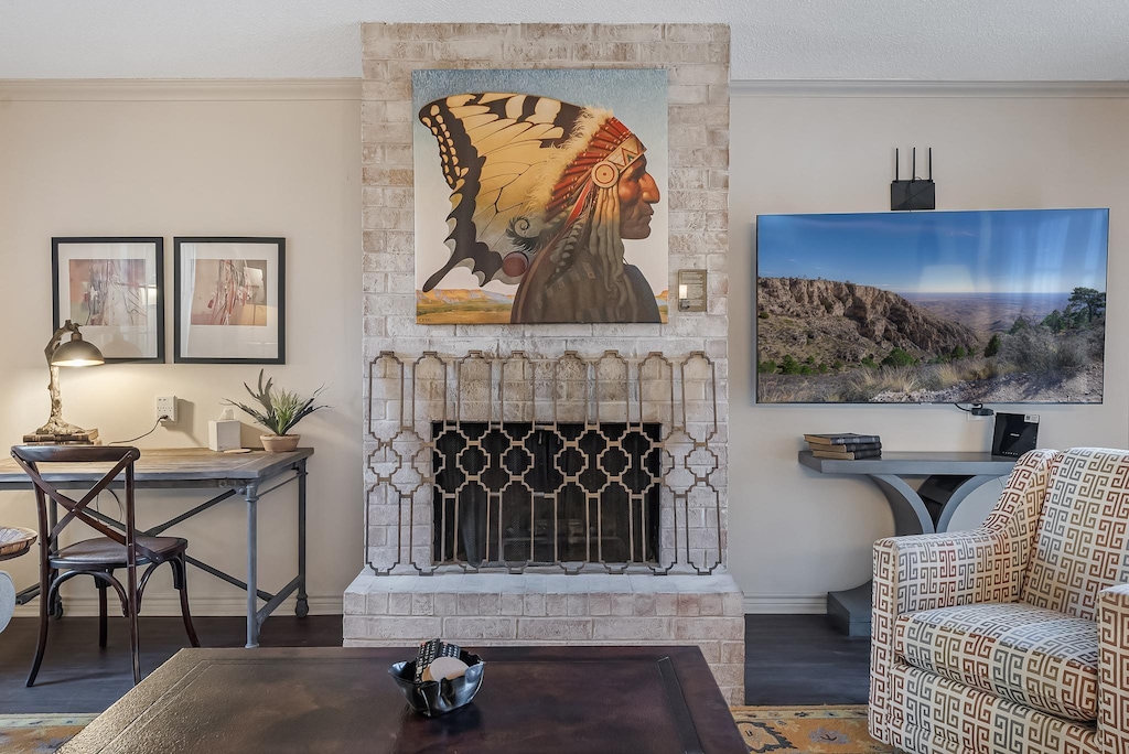 living room featuring a brick fireplace, dark wood-type flooring, and ornamental molding