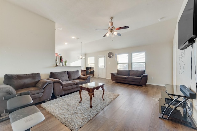 living room featuring ceiling fan with notable chandelier and light hardwood / wood-style floors