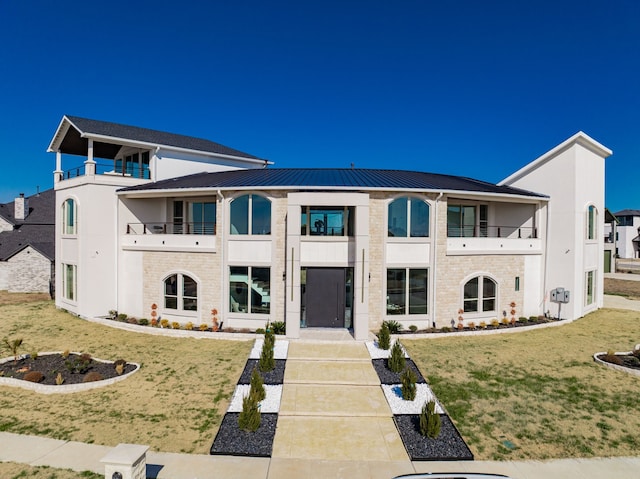 view of front of property featuring a front lawn and a balcony