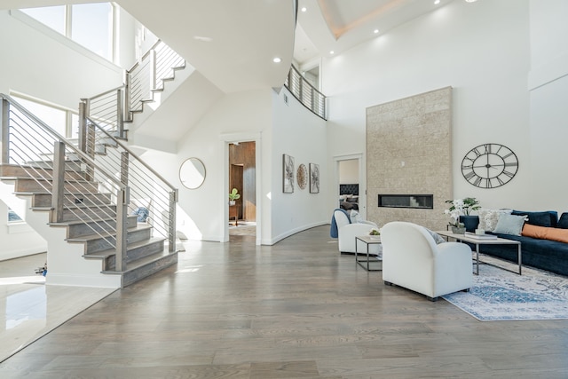 living room with hardwood / wood-style flooring, a tile fireplace, and a high ceiling