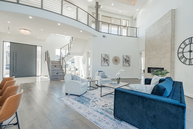 living room with a tiled fireplace, hardwood / wood-style floors, and a high ceiling