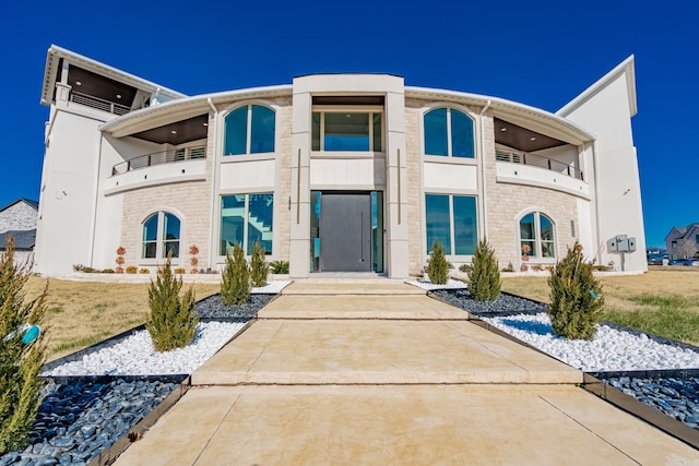 view of front of house with a balcony and a front yard