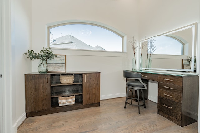 office space with built in desk and light hardwood / wood-style flooring