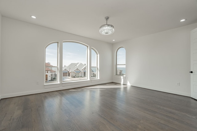 spare room with dark wood-type flooring and an inviting chandelier