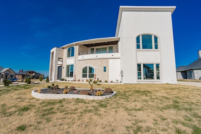 rear view of house with a balcony and a lawn