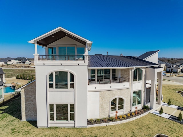 rear view of house with a balcony and a yard