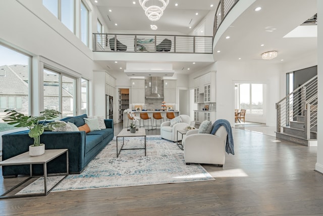 living room with hardwood / wood-style flooring, a towering ceiling, and an inviting chandelier