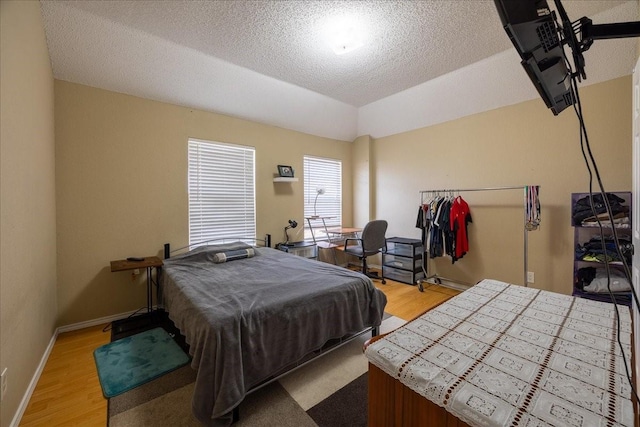 bedroom with lofted ceiling, a tray ceiling, light hardwood / wood-style floors, and a textured ceiling