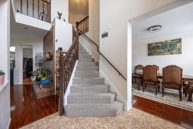 staircase featuring tile patterned flooring, a towering ceiling, and a textured ceiling