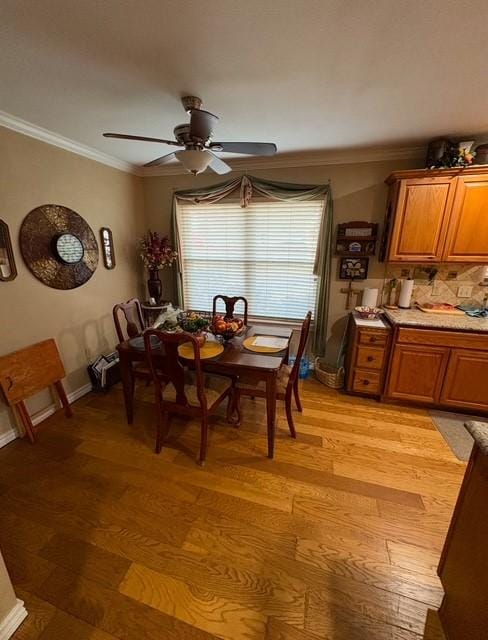 dining area with ceiling fan, ornamental molding, and light hardwood / wood-style flooring