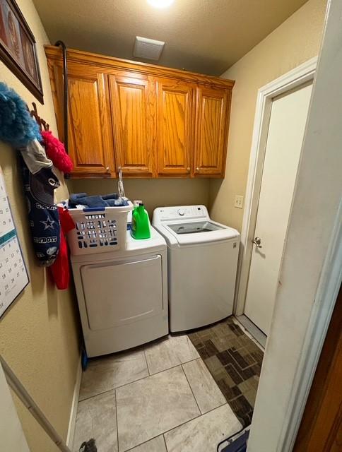 washroom featuring independent washer and dryer, cabinets, and light tile patterned floors