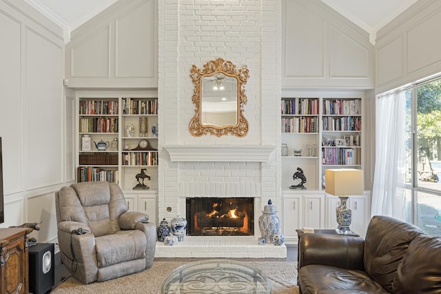 living area with built in shelves, ornamental molding, and a brick fireplace