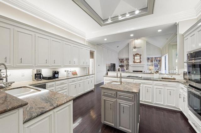 kitchen with lofted ceiling, stone countertops, kitchen peninsula, and a center island with sink