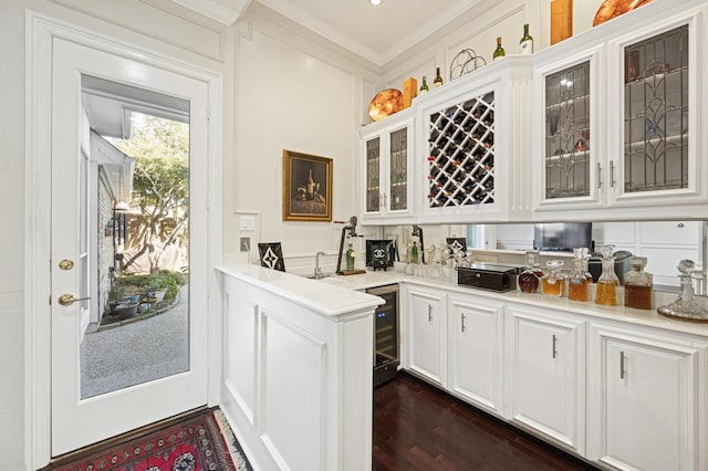 bar with white cabinetry, dark hardwood / wood-style floors, beverage cooler, and crown molding