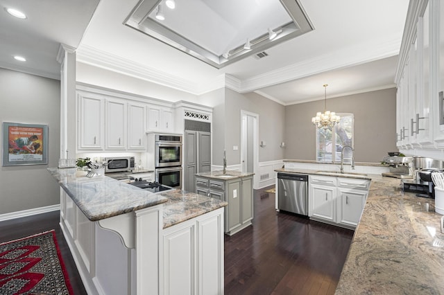 kitchen with stainless steel appliances, a center island, light stone countertops, white cabinets, and kitchen peninsula