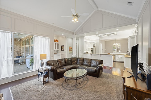 living room with dark wood-type flooring, ceiling fan, ornamental molding, and vaulted ceiling