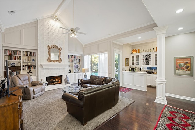 living room with a brick fireplace, dark wood-type flooring, ornamental molding, and decorative columns