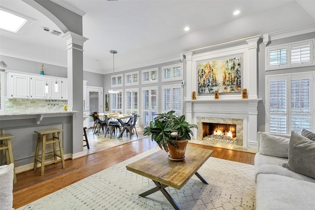 living room featuring ornamental molding, a fireplace, hardwood / wood-style floors, and ornate columns