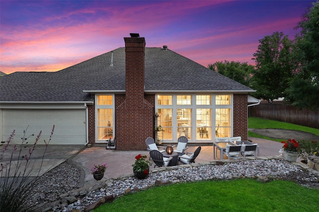 back house at dusk with a patio, a fire pit, and a garage