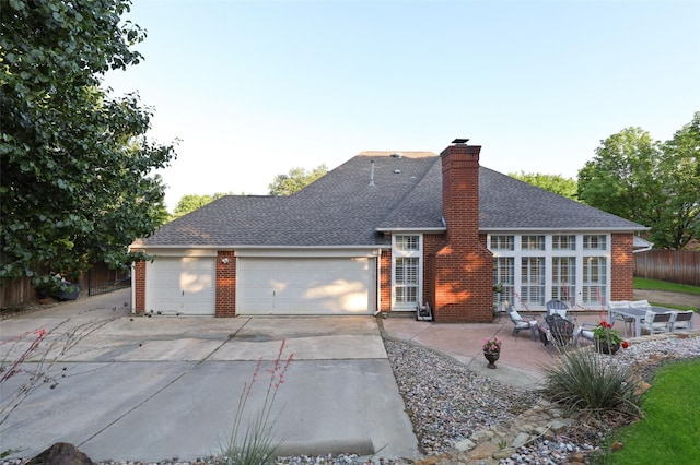 rear view of property with a garage and a patio