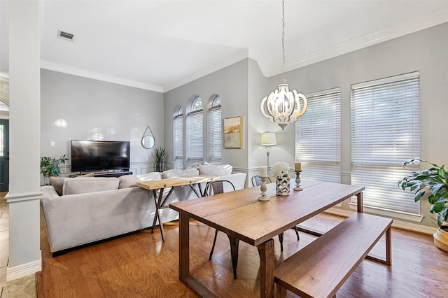 dining room with hardwood / wood-style flooring, ornamental molding, and an inviting chandelier