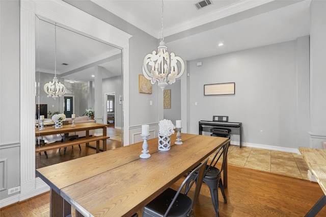 dining space featuring crown molding, wood-type flooring, and a chandelier