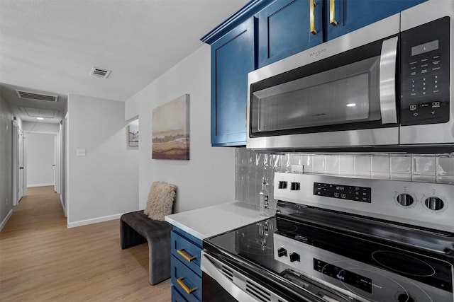 kitchen with blue cabinetry, appliances with stainless steel finishes, and light hardwood / wood-style flooring