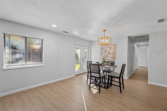 dining area with light wood-type flooring, french doors, and a textured ceiling