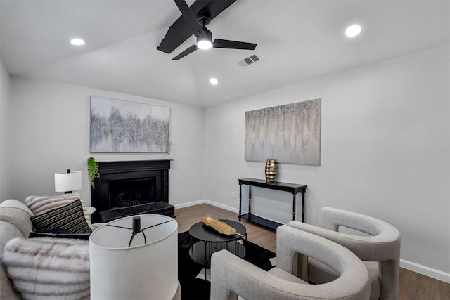 living room with dark wood-type flooring, vaulted ceiling, and ceiling fan