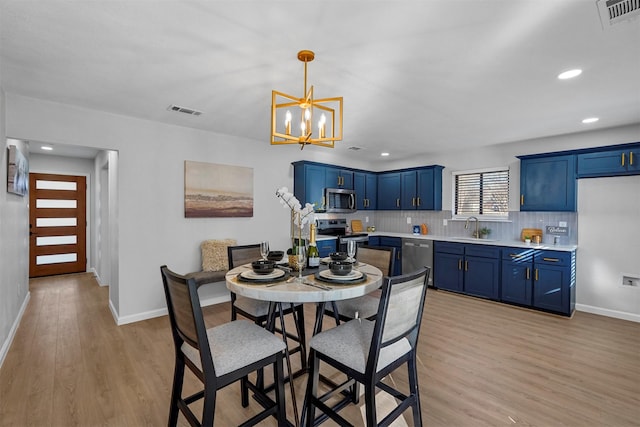 dining room featuring light hardwood / wood-style flooring, sink, and a notable chandelier