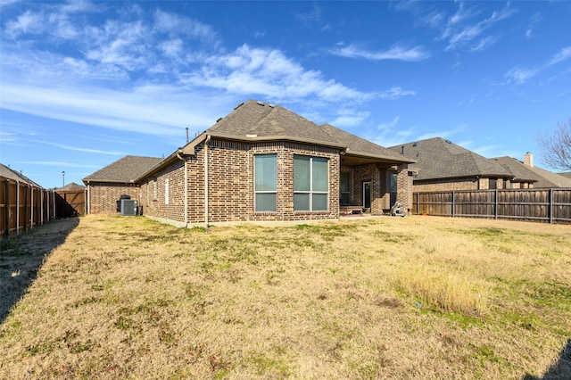 rear view of house featuring a yard and central AC unit