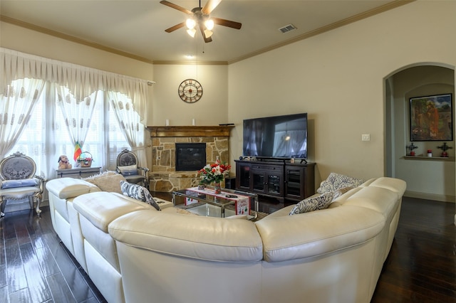 living room with dark wood-type flooring, ceiling fan, a fireplace, and crown molding