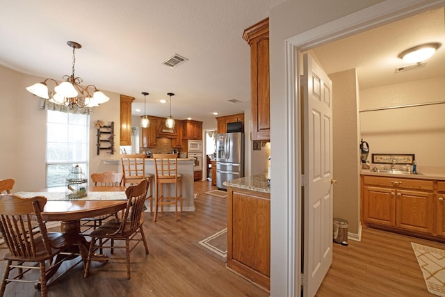 dining room featuring an inviting chandelier, sink, and hardwood / wood-style flooring