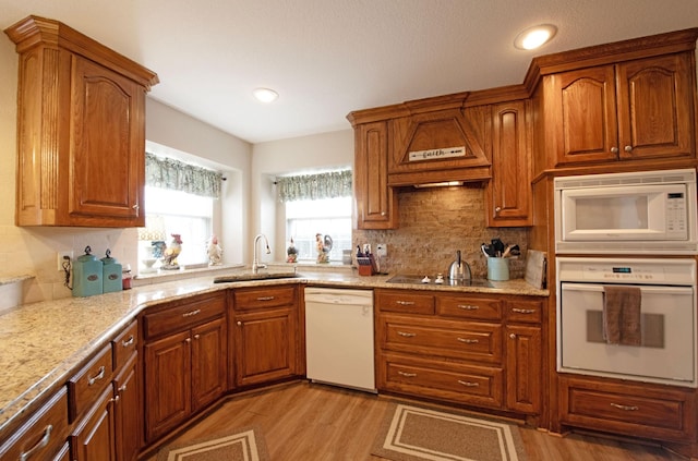 kitchen featuring tasteful backsplash, sink, light wood-type flooring, light stone countertops, and white appliances