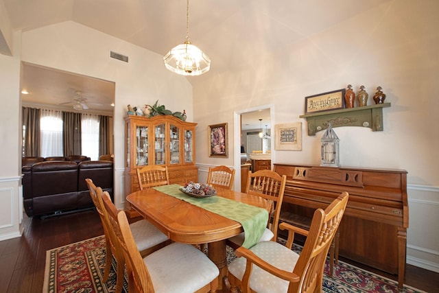 dining space featuring ceiling fan with notable chandelier, dark wood-type flooring, and high vaulted ceiling