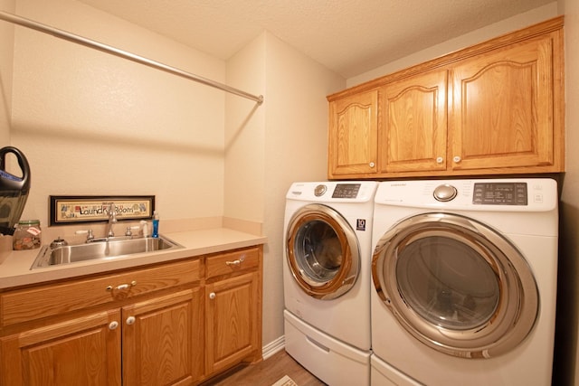 laundry area with sink, hardwood / wood-style flooring, cabinets, and independent washer and dryer