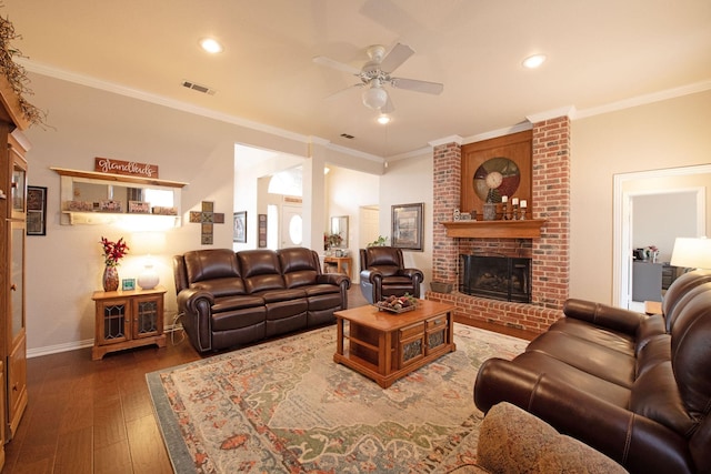 living room with crown molding, a brick fireplace, dark wood-type flooring, and ceiling fan