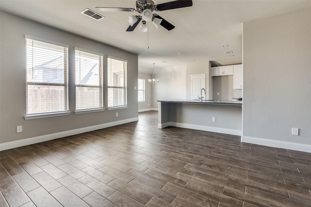 unfurnished living room with ceiling fan with notable chandelier and sink