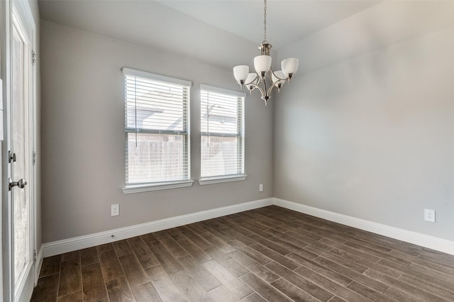 empty room featuring dark wood-type flooring and a notable chandelier